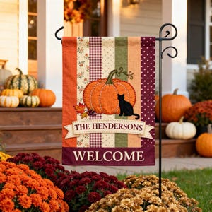 Peut inclure: Un drapeau de jardin rectangulaire avec des bandes verticales orange, à motifs floraux, vichy, vertes et à pois. Une citrouille orange et un chat noir sont représentés au-dessus d'une bannière portant THE HENDERSONS et le mot WELCOME.