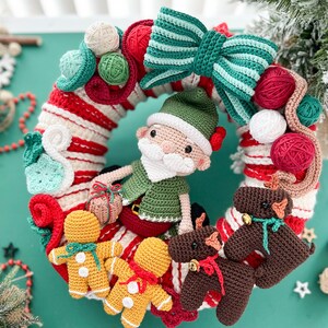 May include: A crocheted Christmas wreath with a green and white striped bow, a green elf with a white beard, and three gingerbread people. The wreath is decorated with red and white candy cane stripes, green and white leaves, and red and white yarn balls.