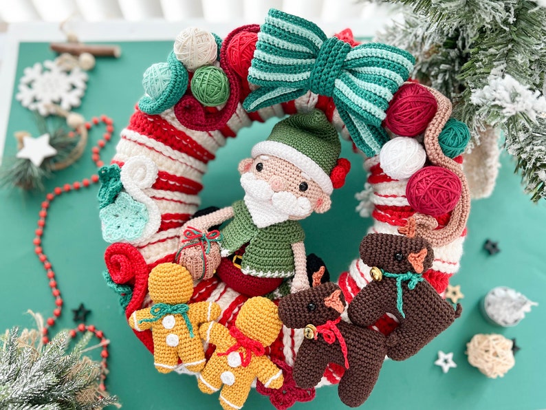 May include: A crocheted Christmas wreath with a green and white striped bow, a green elf with a white beard, and three gingerbread people. The wreath is decorated with red and white candy cane stripes, green and white leaves, and red and white yarn balls.