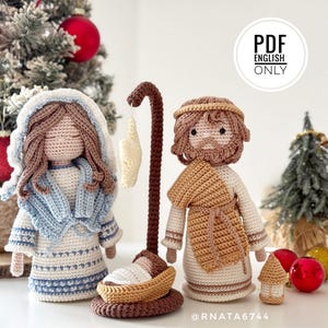 Puede incluir: Set de nacimiento tejido a crochet con una figura en vestido blanco y azul con velo, una figura en túnica blanca y beige, y un bebé en cuna marrón bajo un cayado de pastor marrón. El texto dice PDF ENGLISH ONLY.