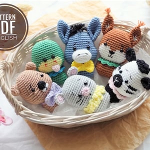 May include: A basket of six crocheted stuffed animals, including a donkey, a squirrel, a frog, a bear, a cat, and a zebra. The animals are all different colors and have different facial expressions. The basket is white wicker.