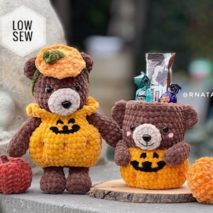 May include: Two brown crochet bears with pumpkin-themed outfits and accessories. One bear wears a pumpkin hat and sweater, while the other sits in a pumpkin-shaped basket. Includes two small crochet pumpkins and text reading LOW SEW.