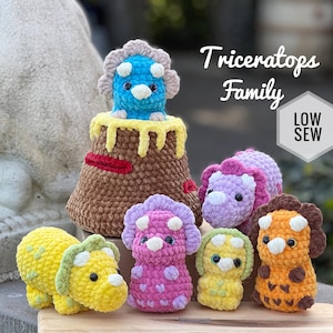 May include: A collection of handmade crochet triceratops dinosaurs in various colors, including yellow, pink, and orange. One dinosaur is atop a brown volcano with yellow lava. The text "Triceratops Family" and "LOW SEW" are also visible.