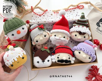 May include: A collection of eight crocheted Christmas ornaments in a box. The ornaments include a snowman, a reindeer, Santa Claus, an elf, a gingerbread person, a Christmas pudding, and two other characters. The ornaments are all handmade and have a variety of colors and textures.