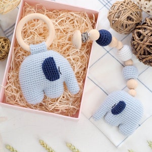 Puede incluir: Un sonajero de elefante de crochet azul con un anillo de madera y un juguete de dentici&oacute;n de crochet azul y blanco con cuentas de madera y un clip.