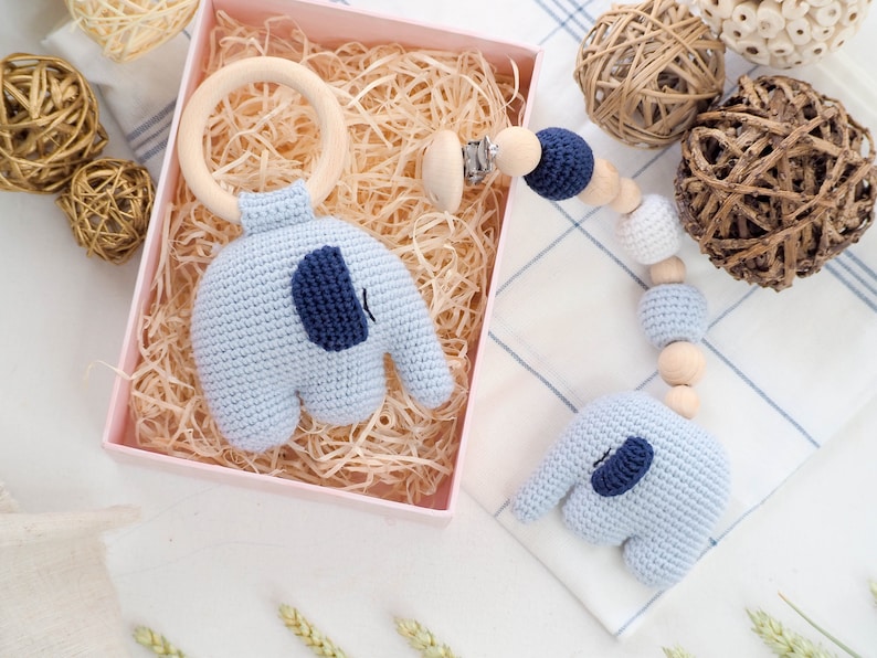 Puede incluir: Un sonajero de elefante de crochet azul con un anillo de madera y un juguete de dentici&oacute;n de crochet azul y blanco con cuentas de madera y un clip.