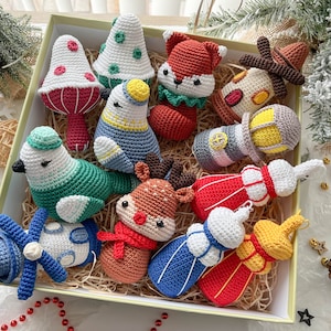 May include: A collection of 11 crocheted Christmas ornaments in a box. The ornaments include a reindeer, a bird, a fox, a mushroom, a lighthouse, a snowman, and a few other whimsical designs. The ornaments are all made with colorful yarn and have a variety of textures.