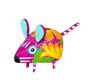 May include: A vibrantly painted decorative mouse figurine. The mouse features a bright pink body, adorned with floral patterns in yellow, orange, and green. It has blue ears and a striped tail, showcasing a folk art style.