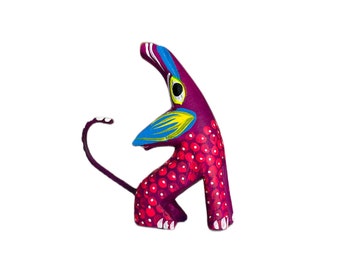 May include: A purple, red, and blue painted wooden animal figurine. The animal has a long tail and a long snout. It is standing on its hind legs.