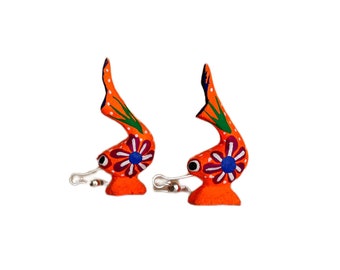 May include: A pair of orange wooden fish ornaments with painted floral details. The fish have silver hooks for hanging.