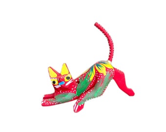 Könnte beinhalten: Eine rote Holzkatzenfigur mit gelben, grünen und blauen Maldetails. Die Katze ist in einer verspielten Pose mit erhobenem Schwanz.