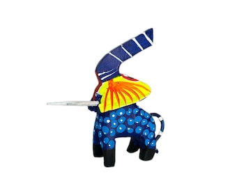 Puede incluir: Una figurita de elefante de madera azul con detalles pintados en amarillo, rojo y blanco. El elefante tiene una trompa larga y un patrón de puntos.