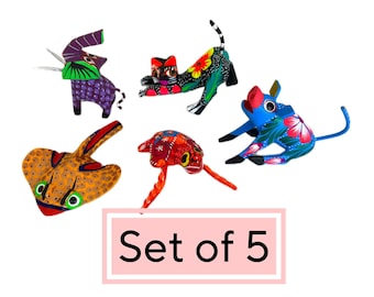 May include: Set of five hand-painted wooden animal figurines. The figurines are brightly colored and feature a variety of animals, including a cat, a pig, a frog, a stingray, and an elephant. The figurines are all standing on a white background. Set of 5.