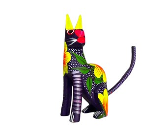 Puede incluir: Una figurita de gato de madera púrpura con detalles florales amarillos, rojos y verdes. El gato está sentado con la cola enroscada alrededor de su cuerpo.