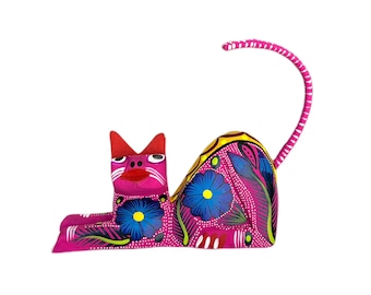 Puede incluir: Una figurita de gato de madera rosa con la cola enroscada. El gato está pintado con flores y hojas coloridas.
