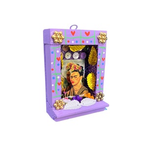 May include: A purple wooden frame with a picture of Frida Kahlo inside. The frame is decorated with gold glitter, sequins, and flowers.