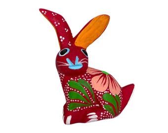 May include: A handcrafted, red wooden rabbit figurine with orange ears and blue accents. The rabbit is decorated with floral patterns in pink, green, and white. This decorative item is a unique piece of folk art.