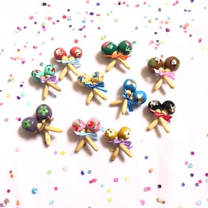 May include: A set of ten colourful maracas with different painted designs. Each maraca is tied with a ribbon.