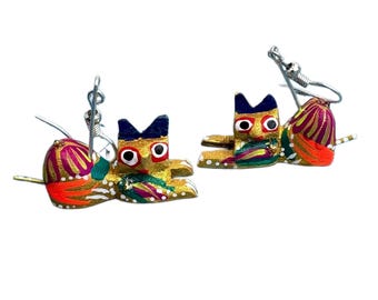 May include: A pair of colorful, handcrafted wooden earrings. Each earring features a stylized cat design with gold, blue, red, and green paint. The earrings have silver-colored ear wires and are set against a white background.