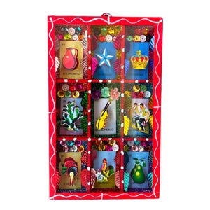 May include: A red wooden frame with nine colorful squares, each containing a different image from a traditional Mexican card game called Loteria. The images include a pitcher, a star, a crown, a cactus, a guitar, a couple dancing, a rooster, a candle, and a pear. Each square has a number and a name in Spanish.