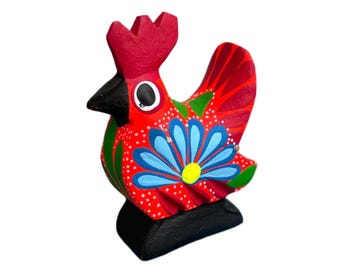 Könnte beinhalten: Handbemalte Holz-Hahn-Figur. Der Hahn hat einen roten Kamm und Schwanz, einen schwarzen Schnabel und einen Körper, der mit blauen Blumen- und grünen Blattmustern auf rotem Hintergrund verziert ist. Er steht auf einem schwarzen Sockel.