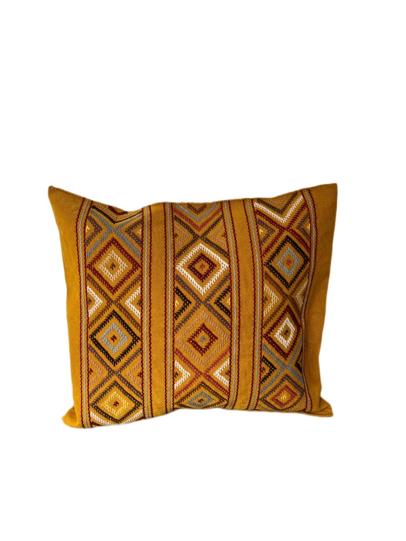 May include: A mustard yellow throw pillow with a geometric pattern in shades of brown, red, and gray.