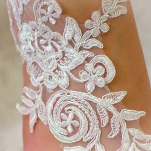May include: White lace fabric with a floral pattern. The lace has a delicate, iridescent sheen.