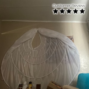 May include: A white tulle petticoat with multiple layers and a circular shape. The petticoat is hanging on a wall and is being used as a decoration.