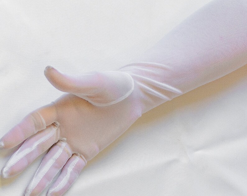 May include: A pair of long white sheer gloves. The gloves are made of a delicate, lightweight fabric and have a smooth, silky texture.