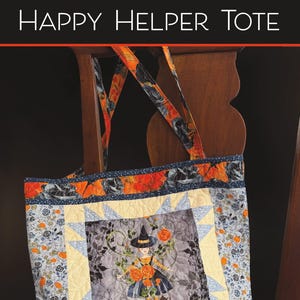 May include: A quilted tote bag featuring the text HAPPY HELPER TOTE and ROBIN PICKENS QUILT PATTERNS. The bag has a central square panel with a witch illustration, surrounded by light yellow star points and floral fabric in orange, blue, and black.