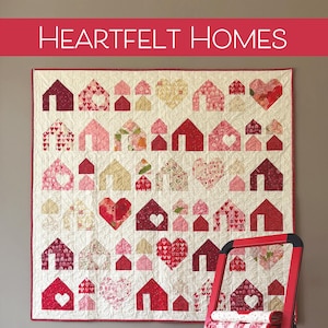 May include: A patchwork quilt featuring a pattern of red and pink houses and hearts, with the words "HEARTFELT HOMES" at the top. A red step ladder holds folded fabric. The Robin Pickens Quilt Patterns logo is at the bottom.