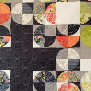 Peut inclure: Une courtepointe color&eacute;e avec un motif g&eacute;om&eacute;trique compos&eacute; de demi-cercles et de carr&eacute;s. La courtepointe comprend divers motifs et couleurs, notamment des imprim&eacute;s floraux, du gris, de l'orange et du noir. Le texte "PARTIAL ECLIPSE ROBIN PICKENS" est visible.