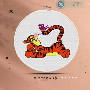 May include: A cross-stitch pattern of a cartoon orange and black tiger with a purple butterfly on a white background. The pattern is framed in a white embroidery hoop.