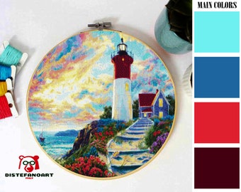 Puede incluir: Un bordado de punto de cruz colorido que representa un faro en una costa rocosa con un cielo azul y nubes. El faro es rojo y blanco con una luz blanca en la parte superior. Hay escalones que conducen al faro desde la costa. El bordado está enmarcado en un aro de madera redondo.