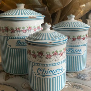 Puede incluir: Tres botes de cerámica vintage con tapas. Los botes son blancos con rayas azules verticales y detalles florales. Las etiquetas dicen "Azúcar", "Pates" y "Chicoree". Las tapas son de rayas azules y blancas.