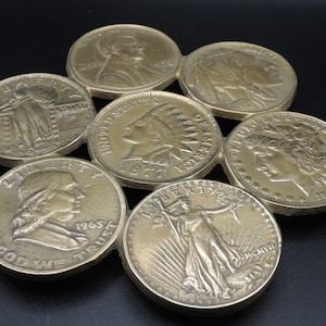 Peut inclure: Une collection de sept pièces de monnaie américaines dorées, chacune représentant un personnage historique différent, disposées en cercle. Les pièces de monnaie datent de différentes années, notamment 1963, 1974, 1976, 1984 et 1927.