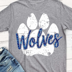 Op de afbeelding: Grijs T-shirt met een witte voetafdruk en het woord "Wolves" in blauwe glitterletters.