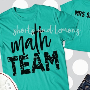 Op de afbeelding: Twee turquoise t-shirts met zwarte tekst. Het grotere shirt zegt "math team" in een verweerd lettertype. Het kleinere shirt zegt "MRS SMITH".