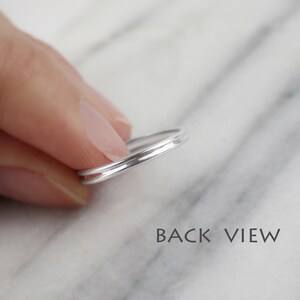 May include: A silver ring with a double band design. The ring is shown from the back, with the two bands visible.