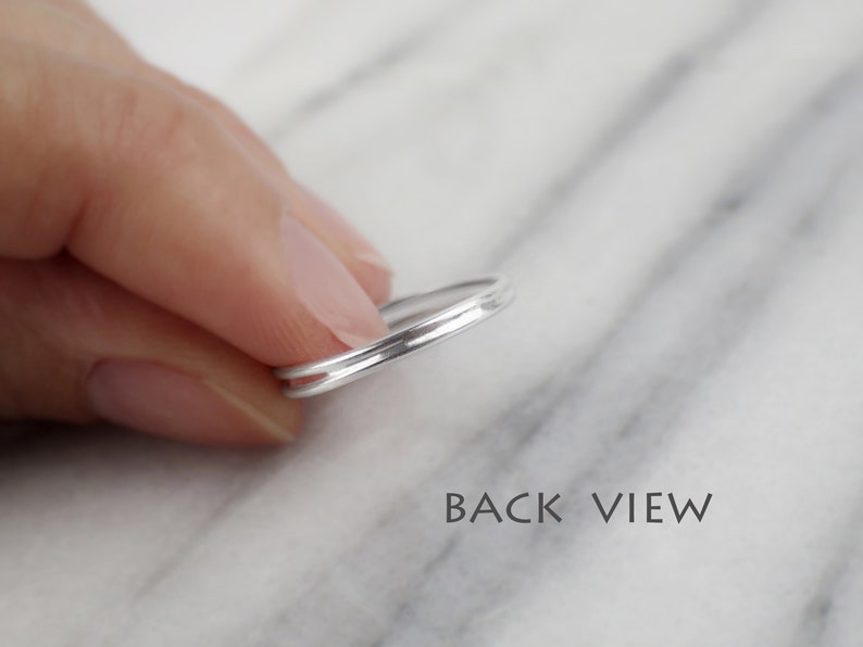 May include: A silver ring with a double band design. The ring is shown from the back, with the two bands visible.
