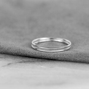 May include: A set of three thin silver rings stacked on top of each other. The rings are smooth and shiny.