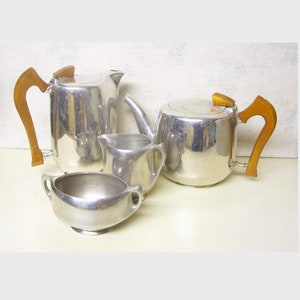 May include: A silver tea set with wooden handles. The set includes a teapot, creamer, sugar bowl, and a coffee pot.