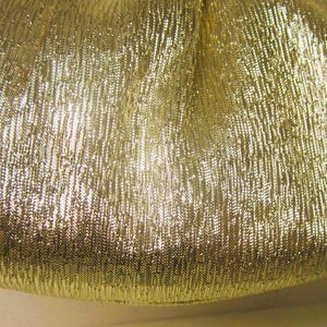 K&ouml;nnte beinhalten: Nahaufnahme einer goldfarbenen, strukturierten Clutch. Die Tasche hat ein gerafftes Design und einen metallischen Glanz. Der Stoff hat ein vertikales, geripptes Muster, das ihm eine einzigartige Textur verleiht. Die Tasche ist wahrscheinlich f&uuml;r Abendveranstaltungen.