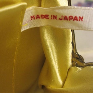 May include: A yellow satin fabric purse with a white label that reads "MADE IN JAPAN".