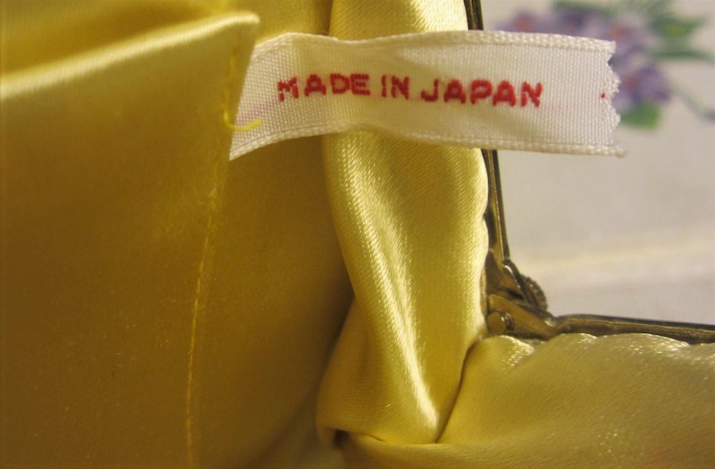 May include: A yellow satin fabric purse with a white label that reads "MADE IN JAPAN".