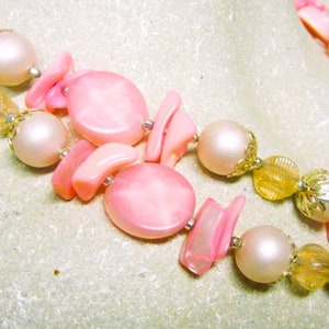 May include: A double strand pink and gold necklace with large pink shell beads and smaller gold beads.