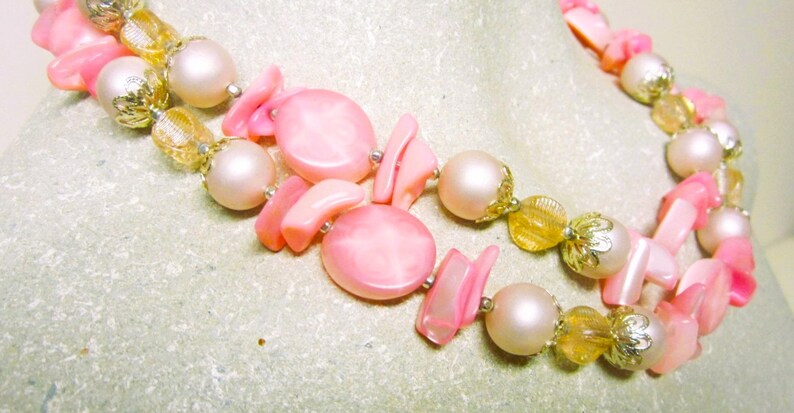 May include: A double strand pink and gold necklace with large pink shell beads and smaller gold beads.