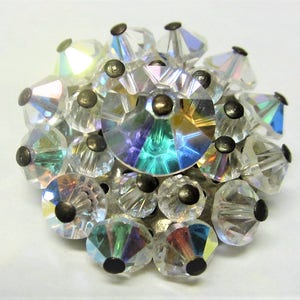 May include: A cluster of iridescent clear glass crystals with silver metal accents. The crystals are arranged in a sphere shape.