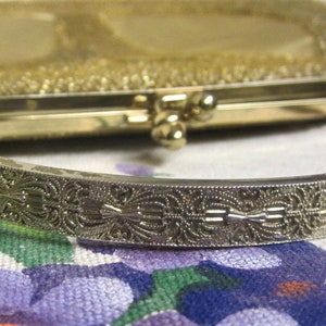 May include: A gold-toned metal purse with a decorative, ornate, silver-toned handle. The purse has a woven, textured design.