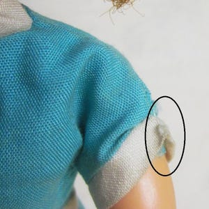 May include: A blue and white doll dress with a white trim around the sleeves. The dress has a short sleeve and a skirt with a white stripe.